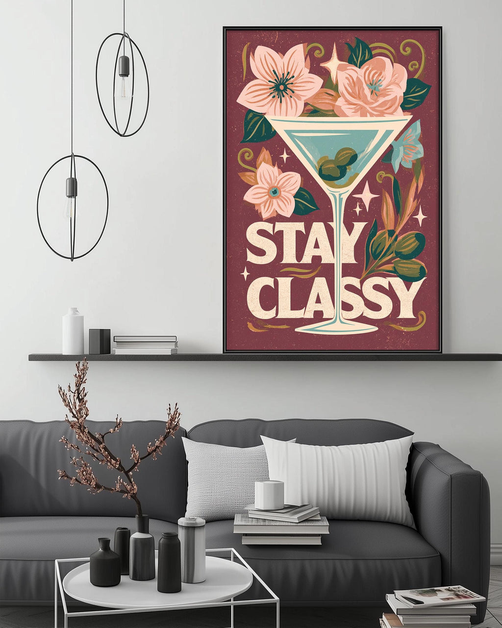 a large framed poster with a floral design and the text "STAY CLASSY" hanging on a wall above a gray couch with decorative items on it.