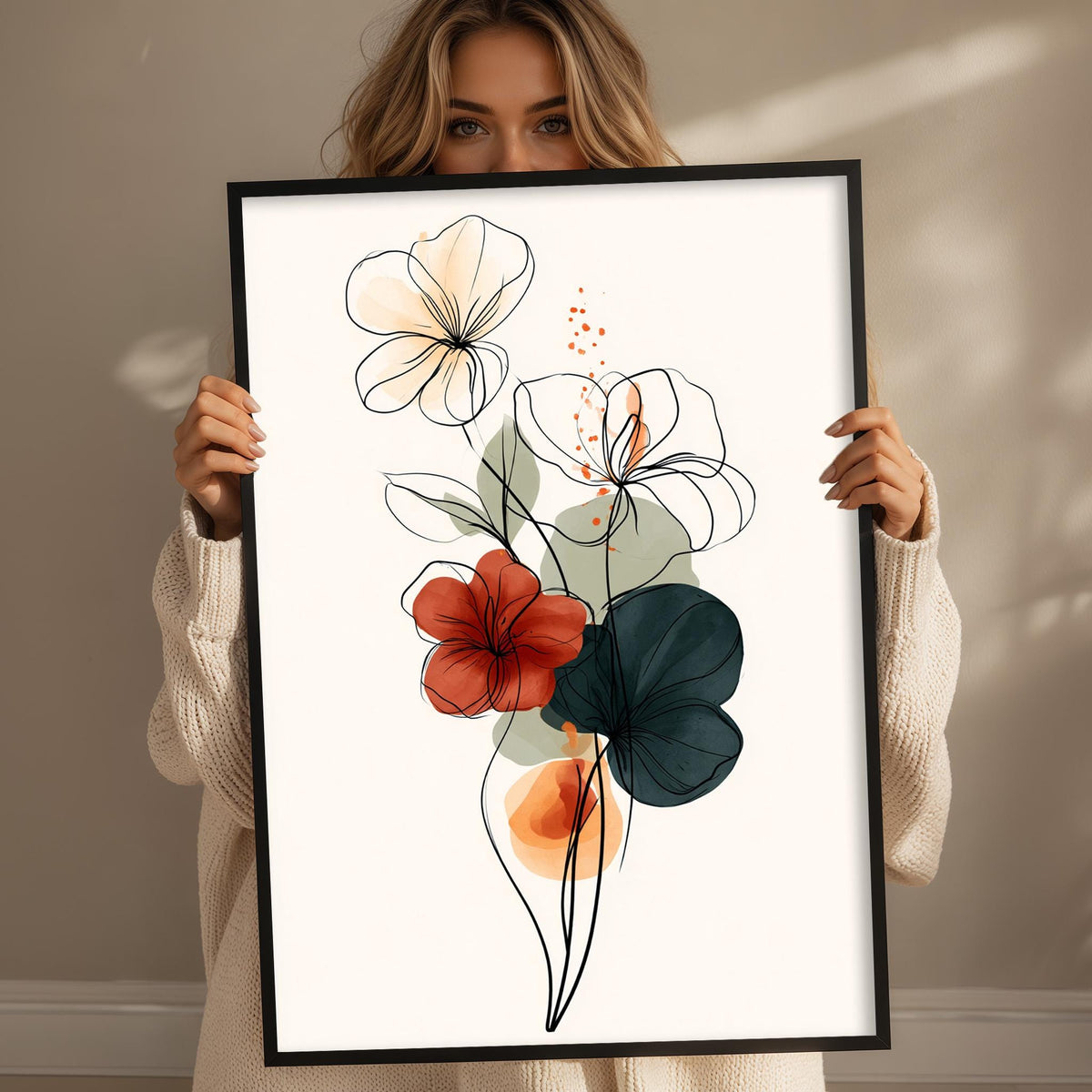 A woman is holding up a framed print of a floral design with various colored flowers.