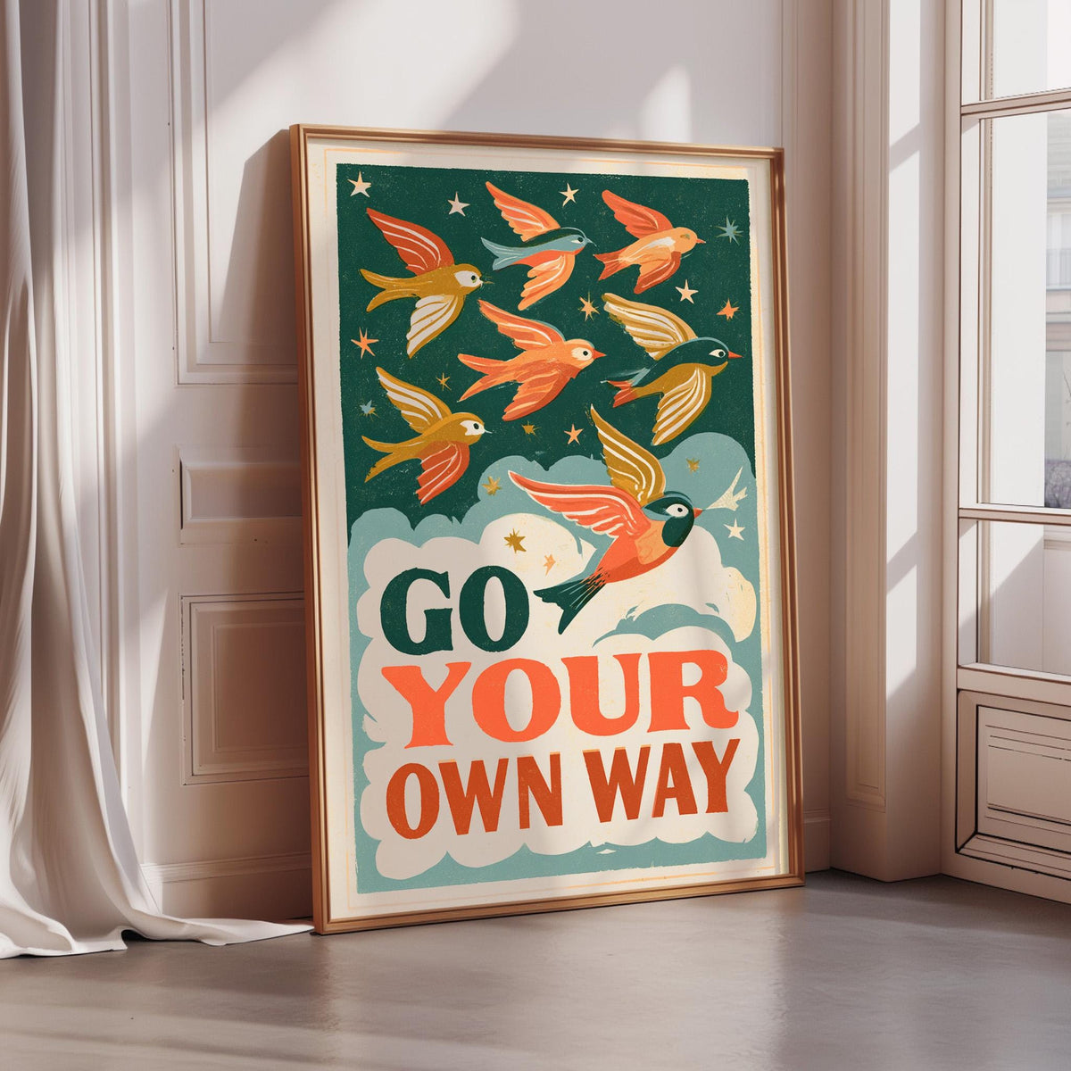 A framed poster with a vibrant illustration of birds flying against a starry night sky, accompanied by the text "GO YOUR OWN WAY".