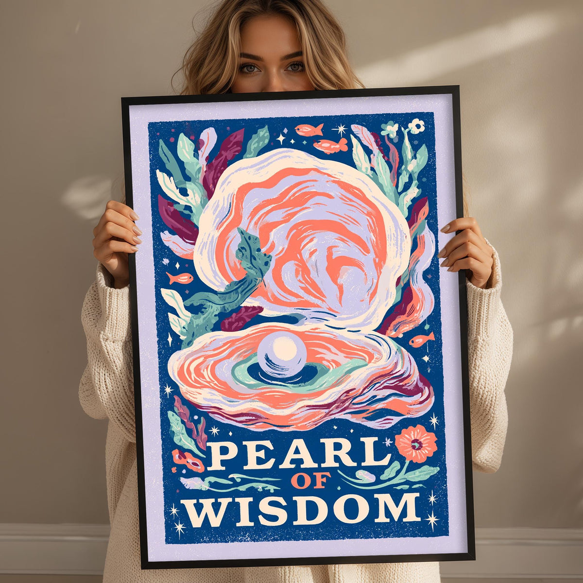 A woman is holding up a framed poster with a colorful illustration of an oyster shell and the text "PEARL OF WISDOM" on it.
