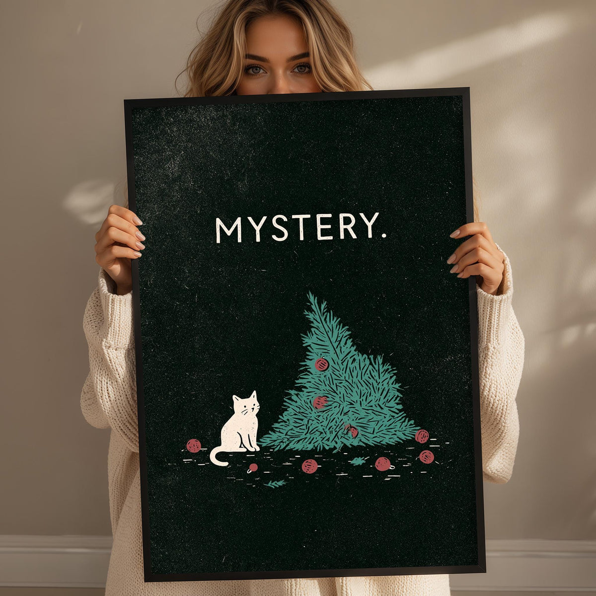 A woman holding a framed poster with a cat sitting on a Christmas tree.