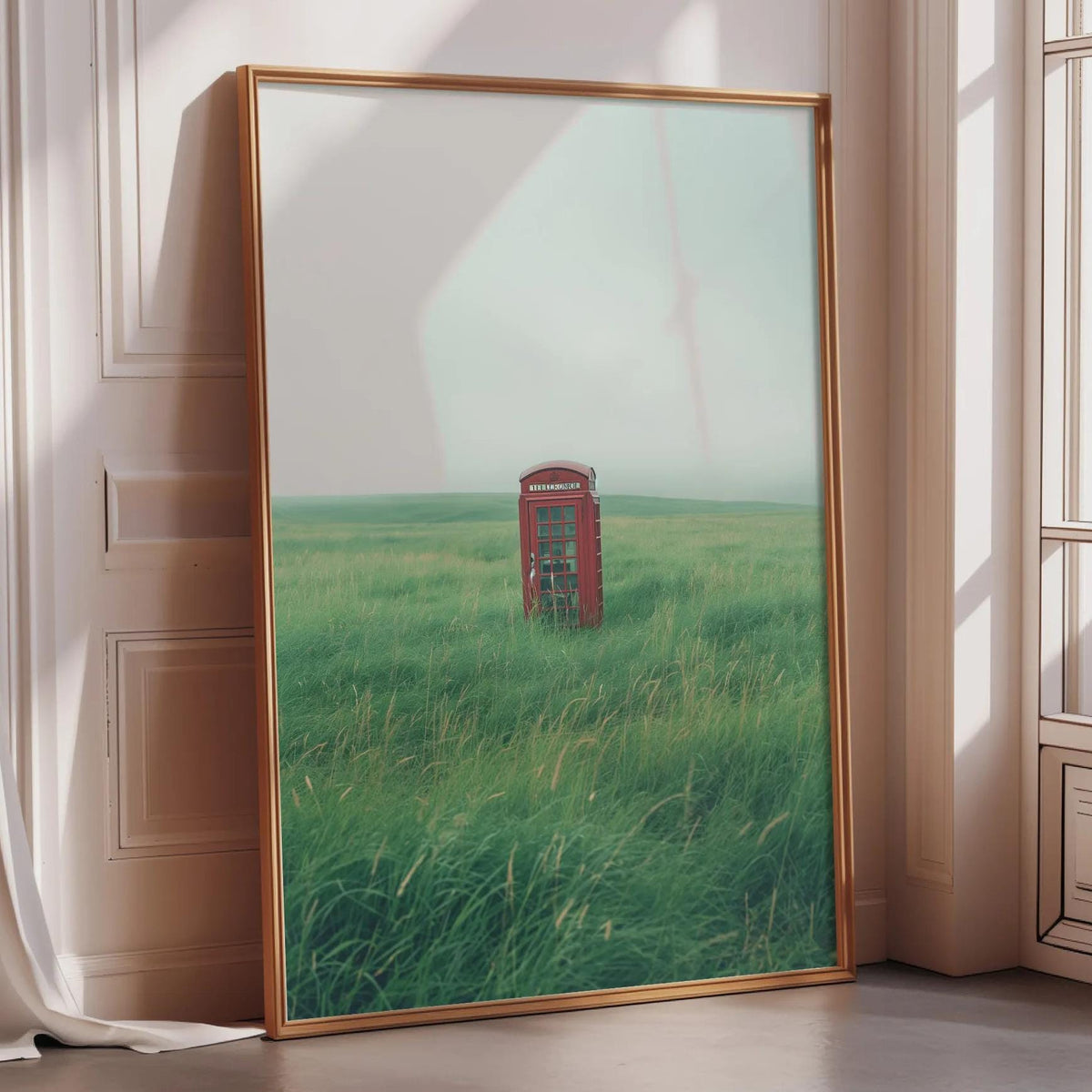A large framed picture depicting a red telephone booth in a grassy field, with a hazy sky in the background.