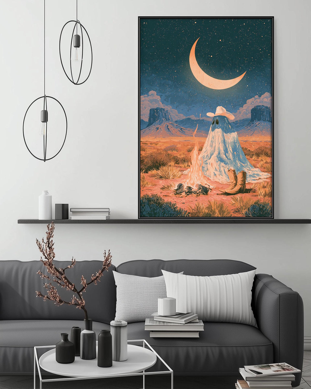 a large, colorful painting of a desert landscape with a crescent moon and stars in the night sky, hanging on a wall above a gray couch with a coffee table in front of it.