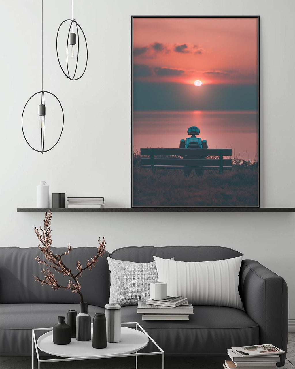 a large framed picture of a person sitting on a bench, with a sunset in the background. The picture is hanging on a wall above a gray couch, which has a coffee table in front of it. The room has a minimalist and modern design, with circular pendant lights hanging from the ceiling and a shelf displaying various decorative items.