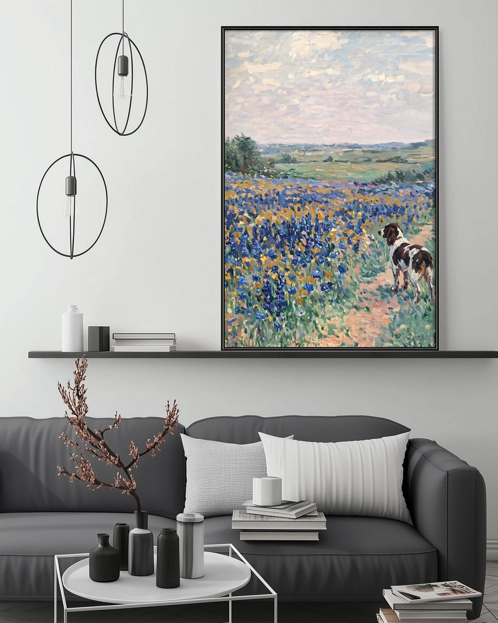 a living room with a gray sofa, a coffee table, and a large painting of a field with a dog in the background. The painting is hanging on the wall above the sofa.