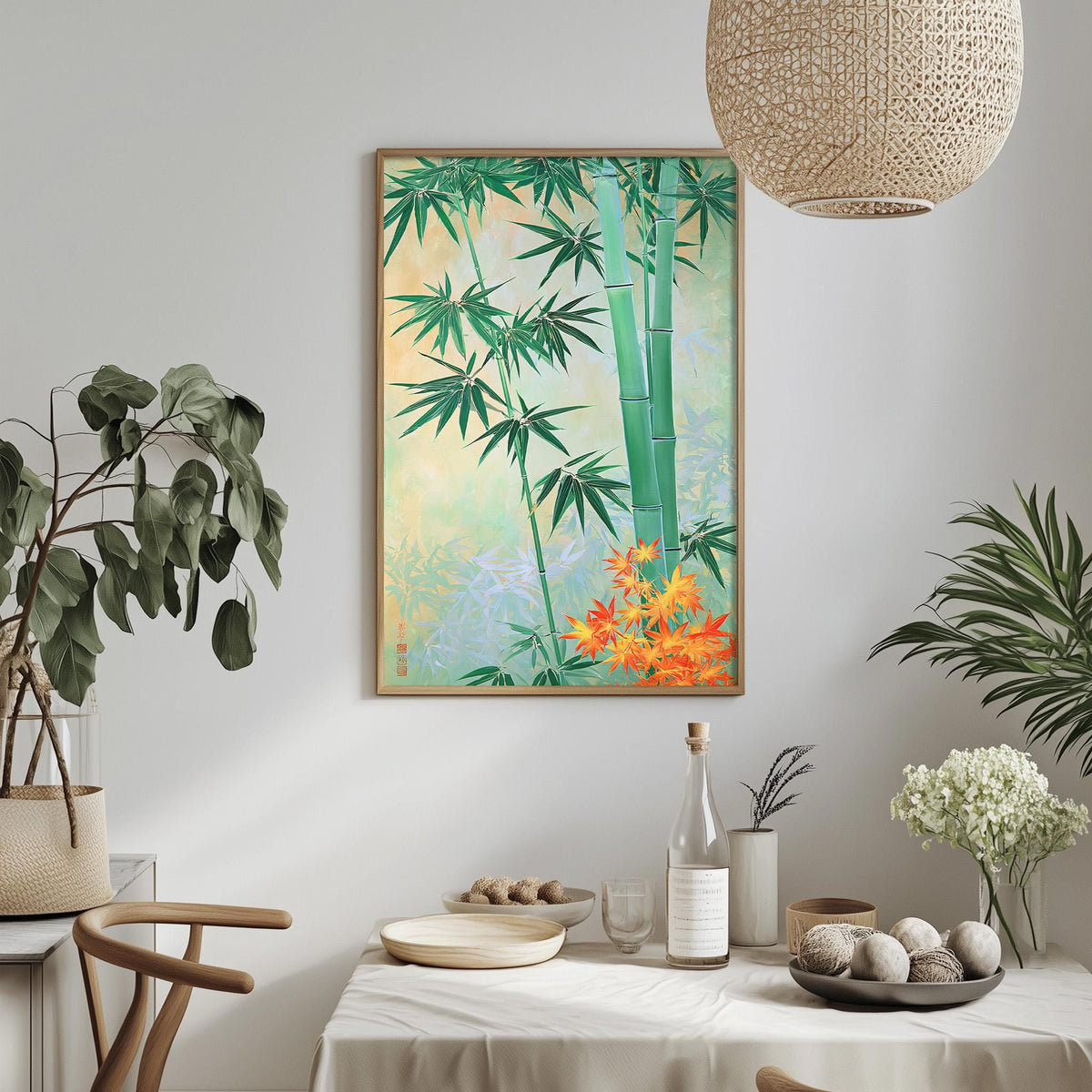 a dining table with a white tablecloth, a bowl of fruit, a bottle, and a vase with flowers. Above the table, there is a framed painting of bamboo plants and flowers.