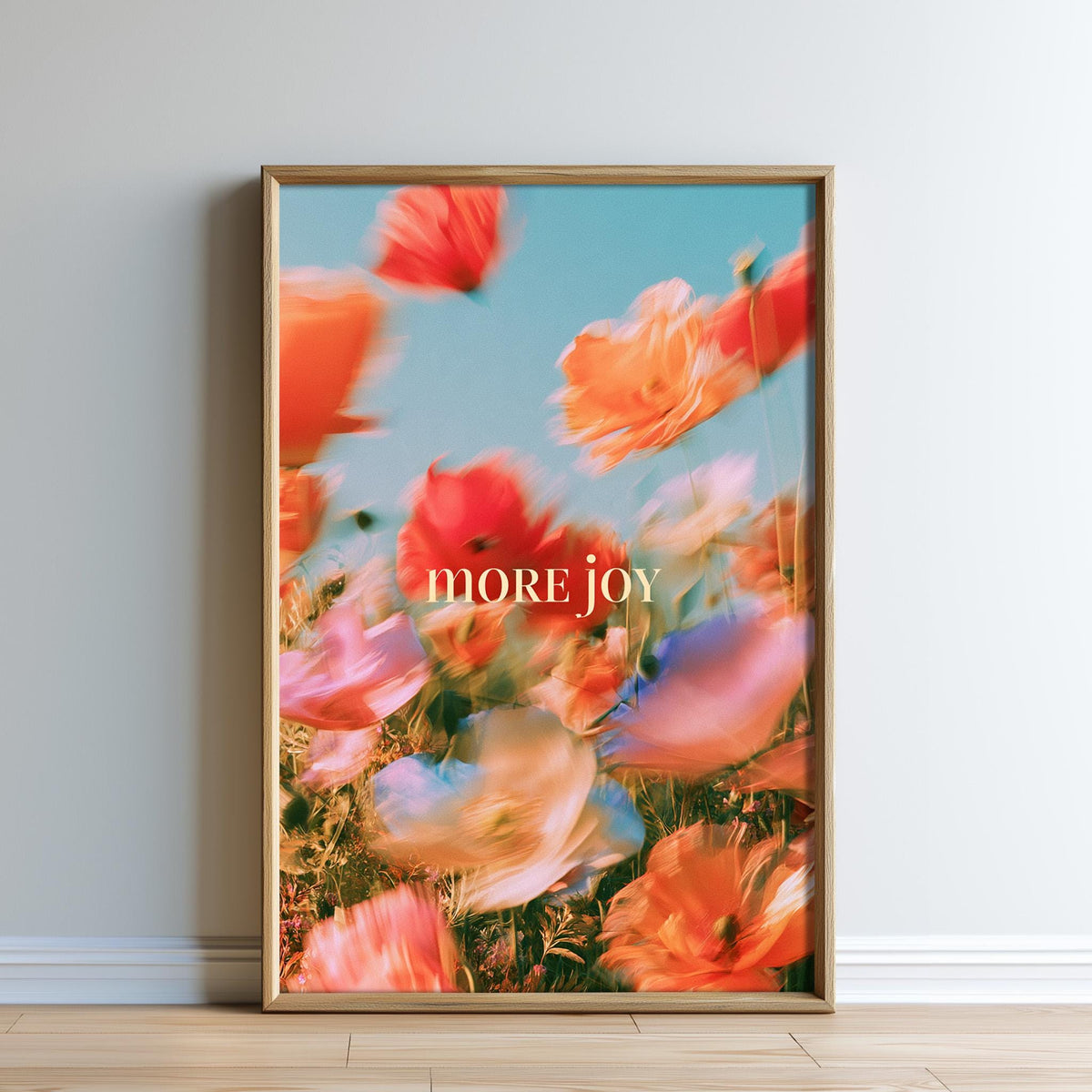 The image is a framed poster with a vibrant, blurred floral background and the text "MORE.JOY" prominently displayed.