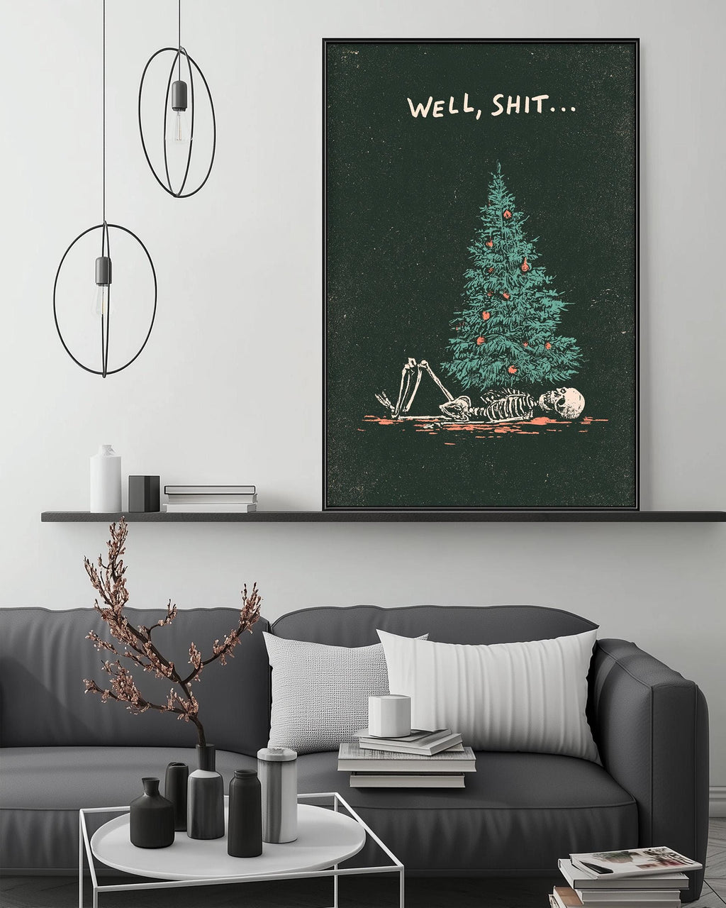 a living room with a gray sofa, a coffee table, and a large framed poster of a skeleton lying on a Christmas tree. The poster has the text "WELL, SHIT..." written on it.
