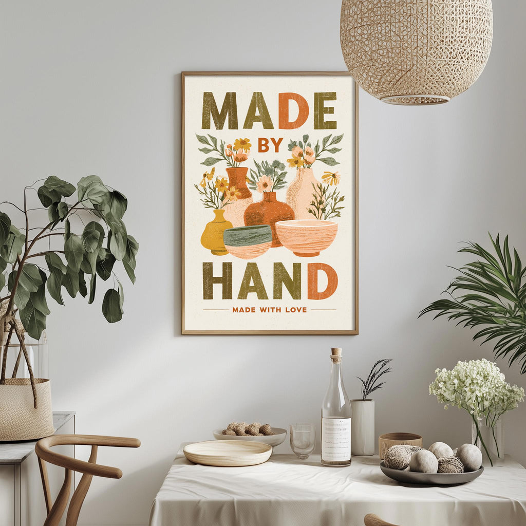 a framed poster with the text "MADE BY HAND MADE WITH LOVE" hanging on a wall above a dining table with various decorative items and plants.