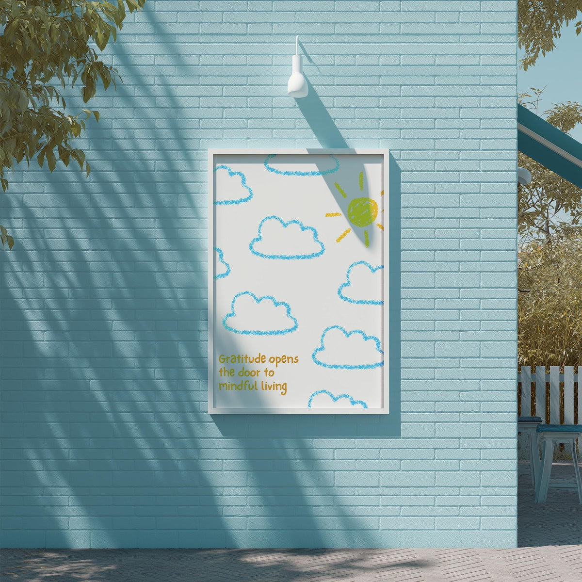 a blue brick wall with a framed poster hanging on it. The poster has a drawing of clouds and a sun, and the text below the drawing says "Gratitude opens the door to mindful living".