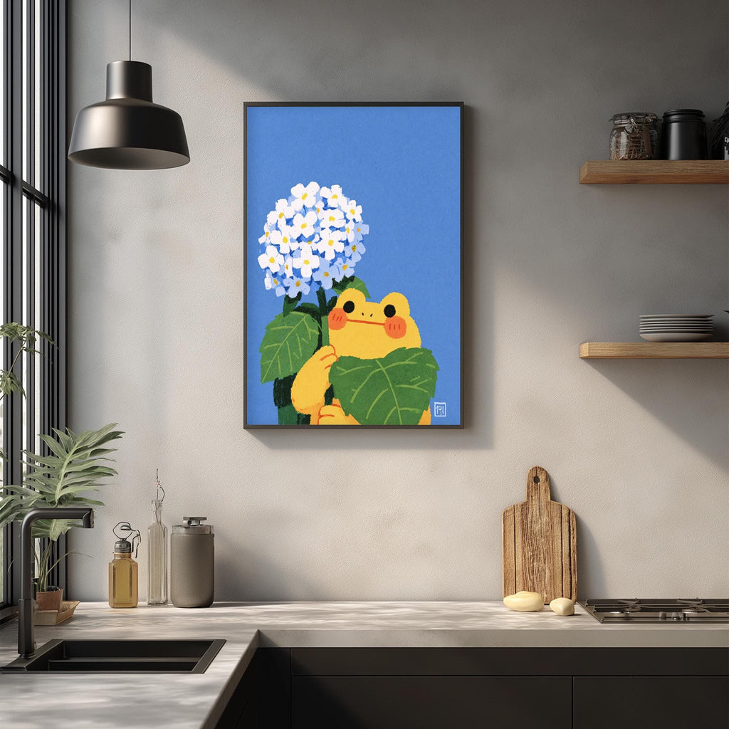 a framed illustration of a frog holding a bunch of white flowers, hanging on a wall above a kitchen counter.