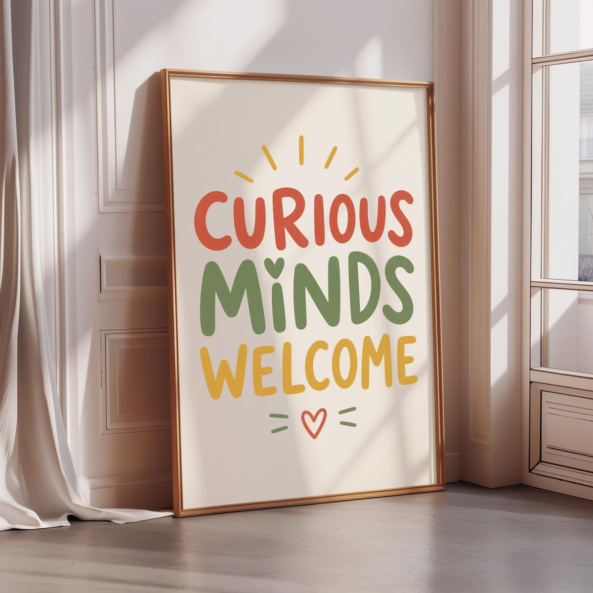 a framed poster with the text "CURIOUS MINDS WELCOME" and a heart symbol, placed on a wooden floor next to a window.