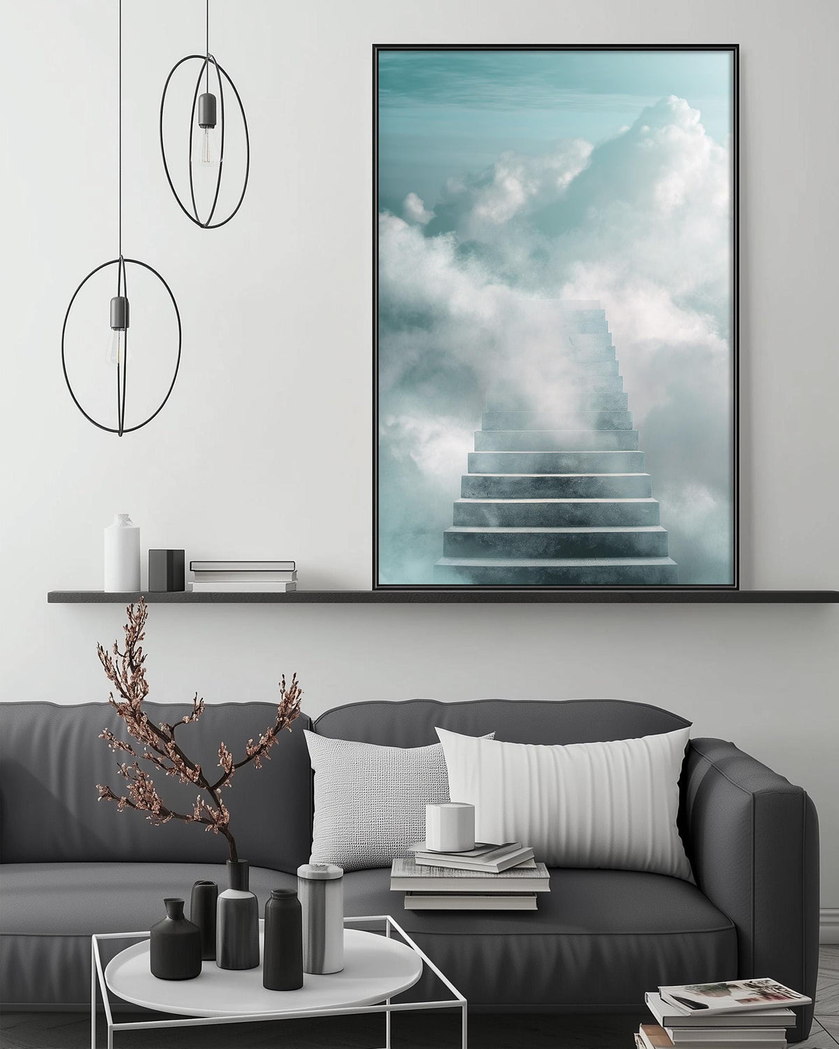 a modern living room with a gray sofa, a coffee table, and a large framed picture of a staircase leading up to a sky filled with clouds.