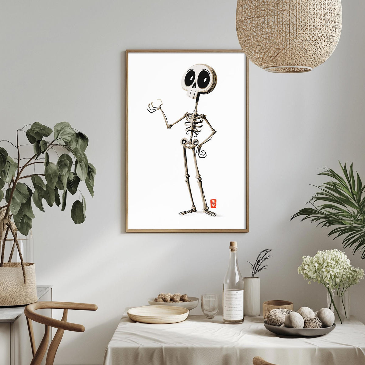 a minimalist dining room with a white tablecloth, a bowl of fruit, a bottle, and a plant. Above the table, there is a framed illustration of a skeleton with a skull-like face.