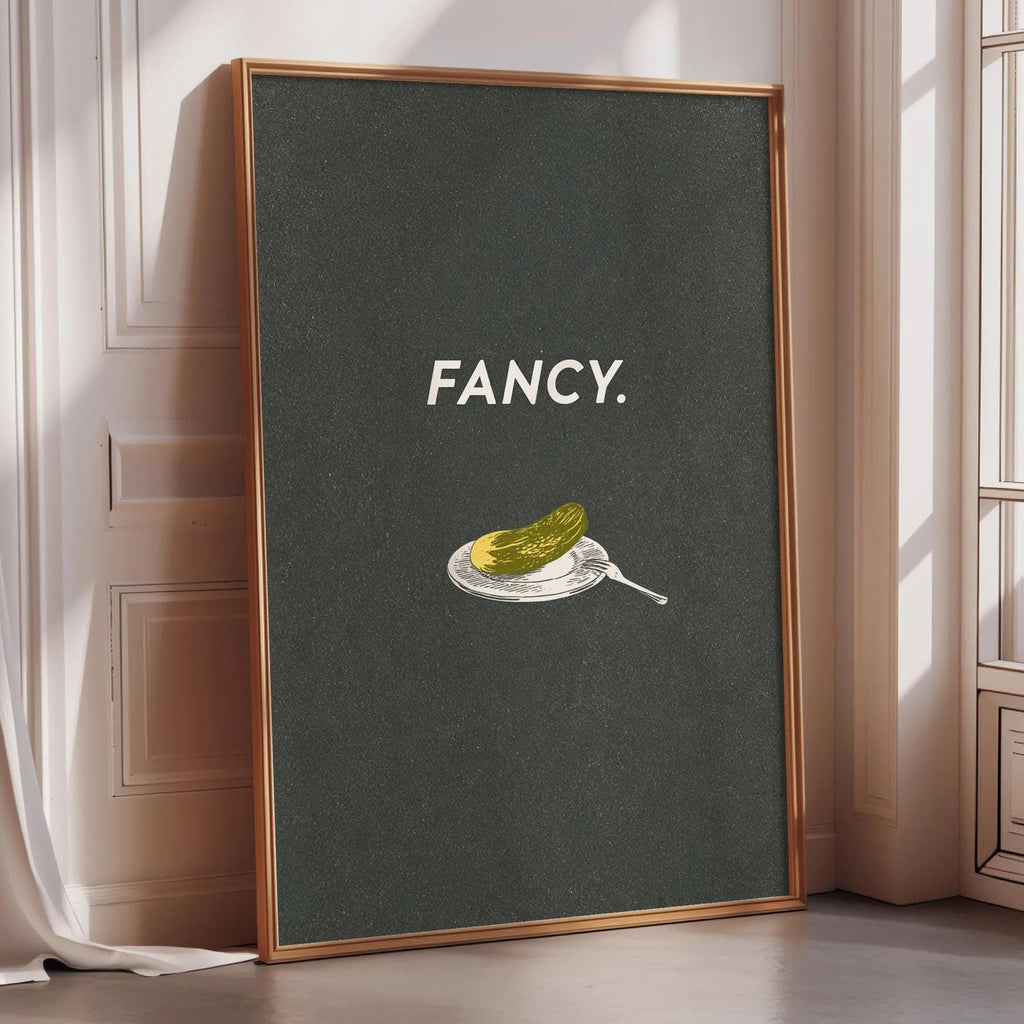 a framed poster with the word "FANCY" written on it, along with an illustration of a pickle on a plate.