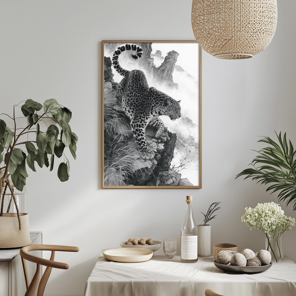 a framed black and white photograph of a leopard on a rocky cliff, hanging on a wall above a dining table with various decorative items and plants.