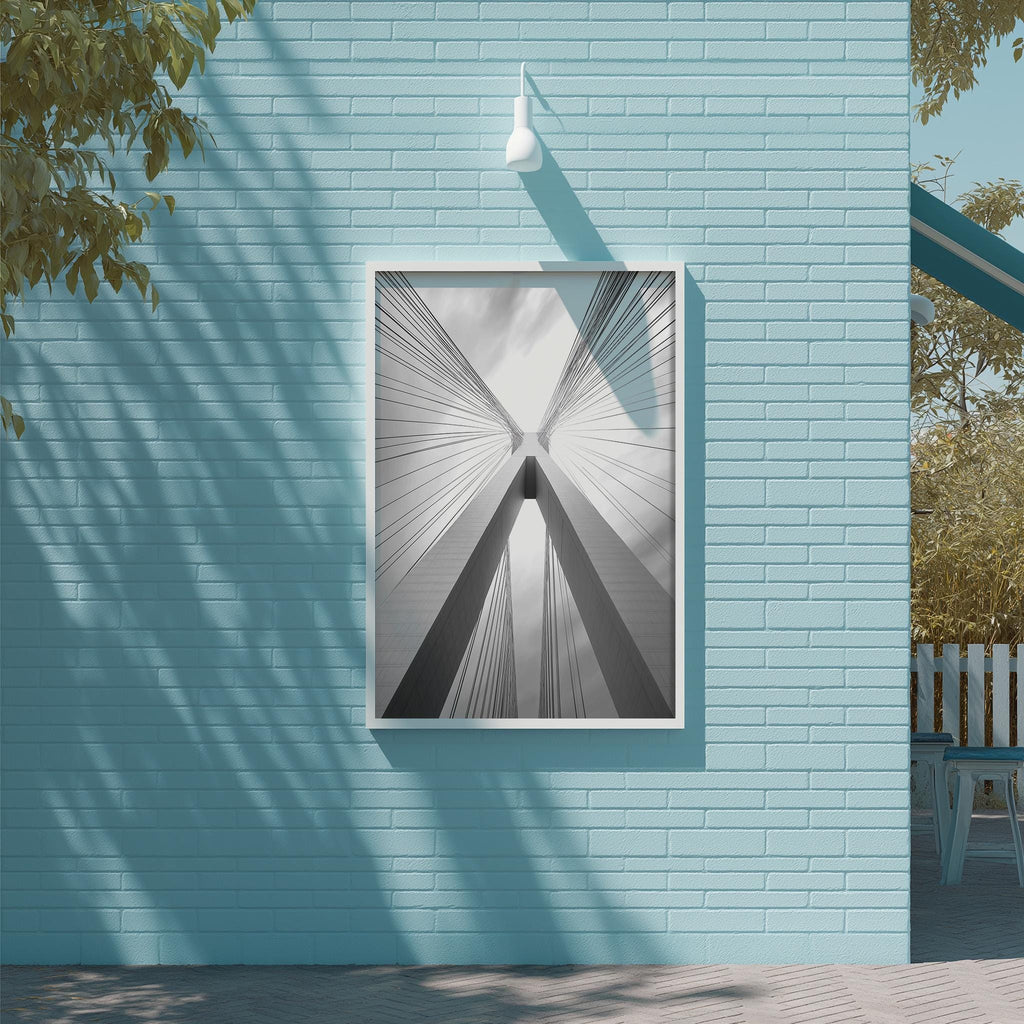 a blue brick wall with a framed black and white photograph of a building's cross-like structure, which appears to be a bridge.