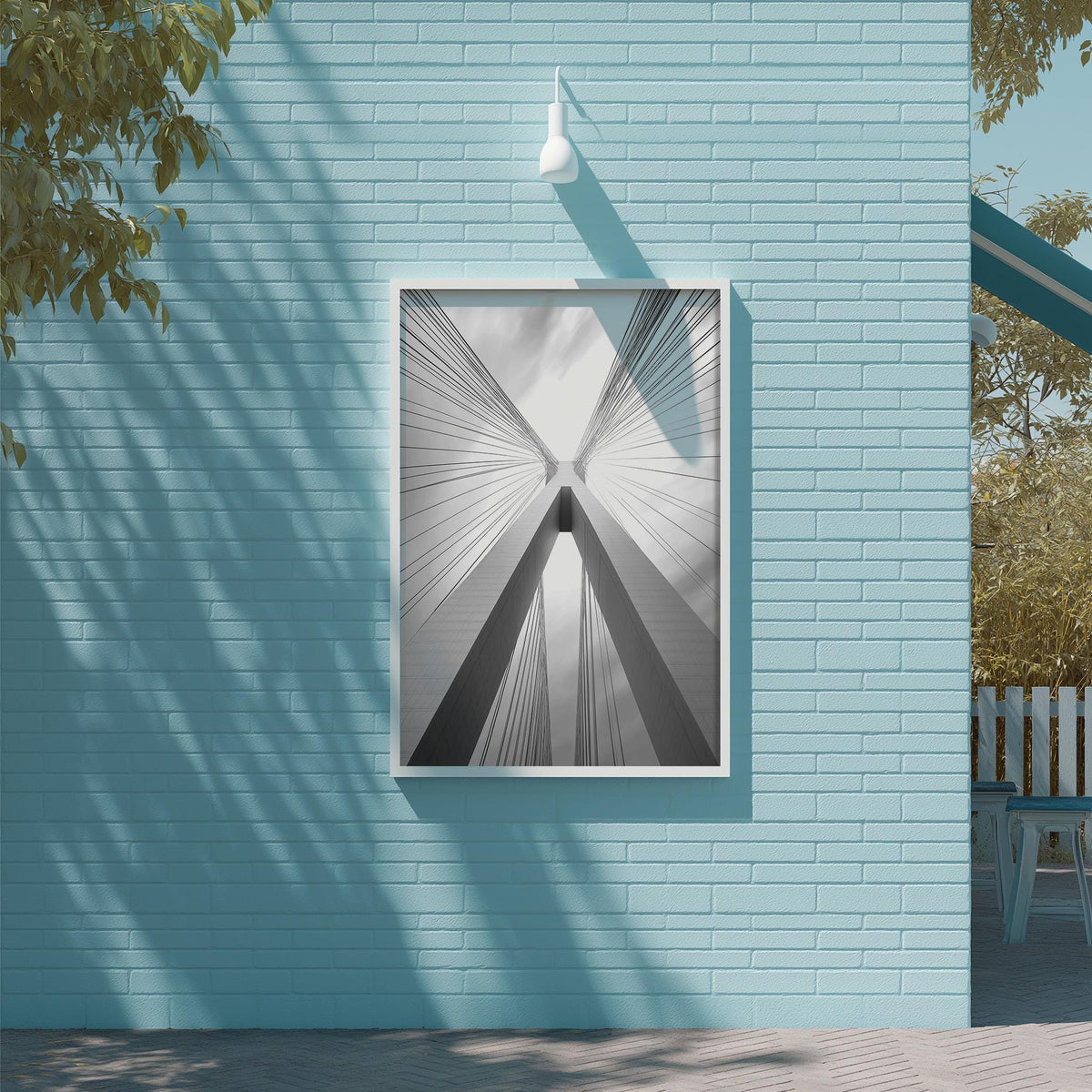 a blue brick wall with a framed black and white photograph of a building's cross-like structure, which appears to be a bridge.