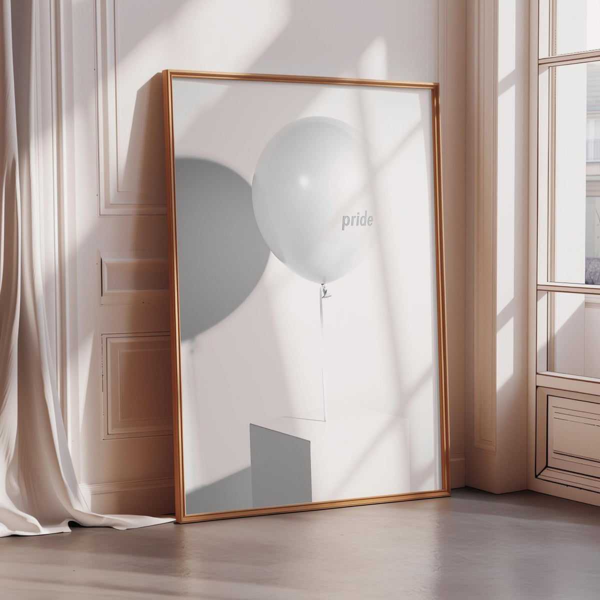 a large framed picture of a white balloon with the word "pride" written on it, placed on a wooden floor in a room with a window.