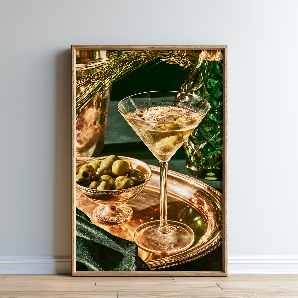 A framed photograph of a martini glass filled with a cocktail, accompanied by a bowl of green olives, set against a dark green background.