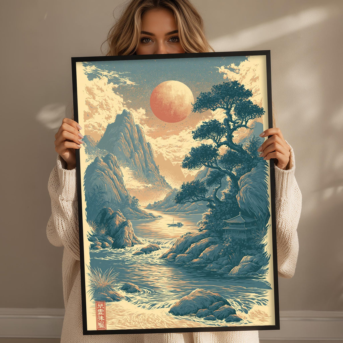 A woman holds up a framed print depicting a serene landscape with mountains, a river, and a large red moon in the sky.
