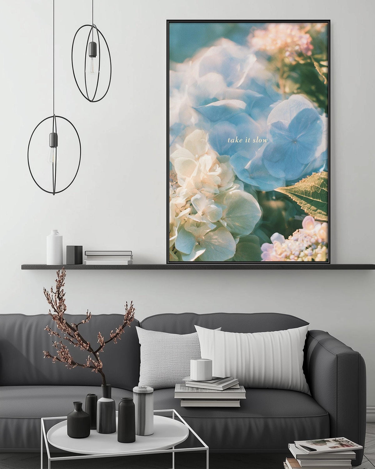 a modern living room with a gray sofa, a coffee table, and a large framed print of flowers hanging on the wall above the sofa.