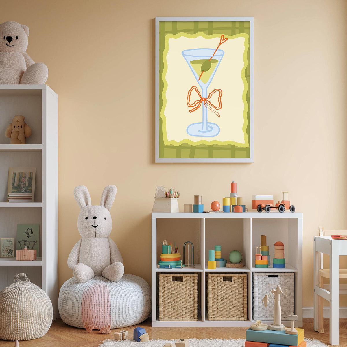 A cozy children's room with a white bookshelf, a plush rabbit, and a colorful toy box filled with toys. A framed illustration of a martini glass with an olive on top is displayed on the wall above the toy box.
