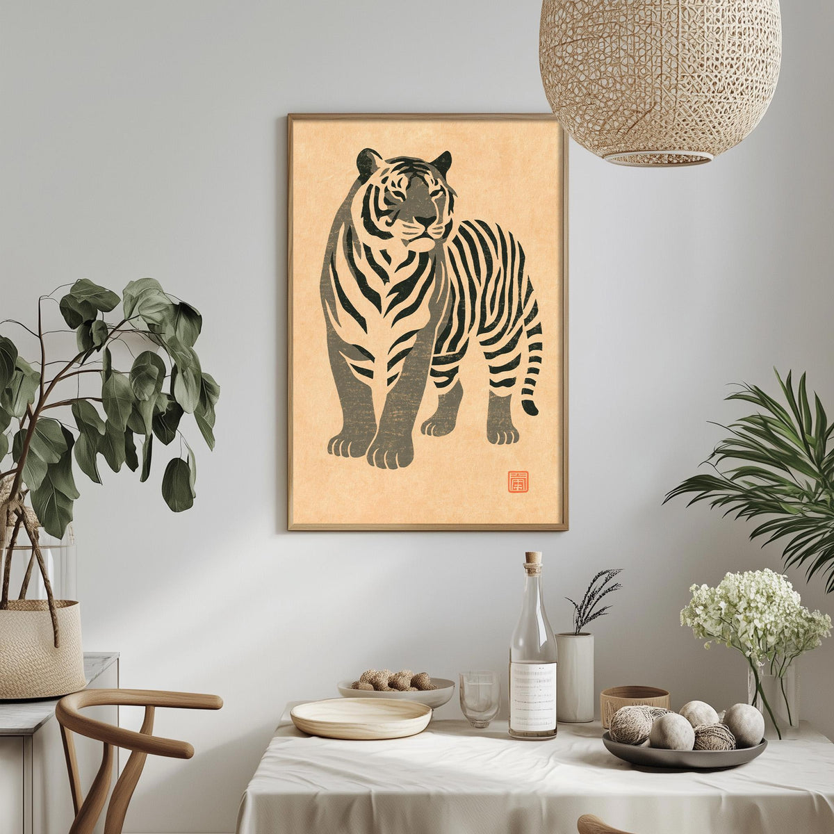 a dining table with a bowl of fruit, a bottle, and a vase of flowers, along with a framed picture of a tiger hanging on the wall above the table.