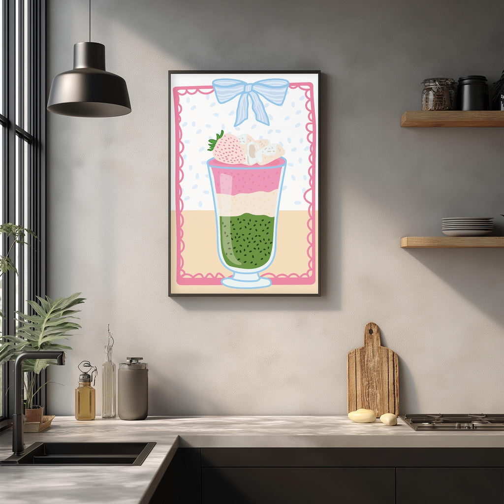 a kitchen counter with various kitchen items, including a framed illustration of a colorful layered drink, a wooden cutting board, and a potted plant.