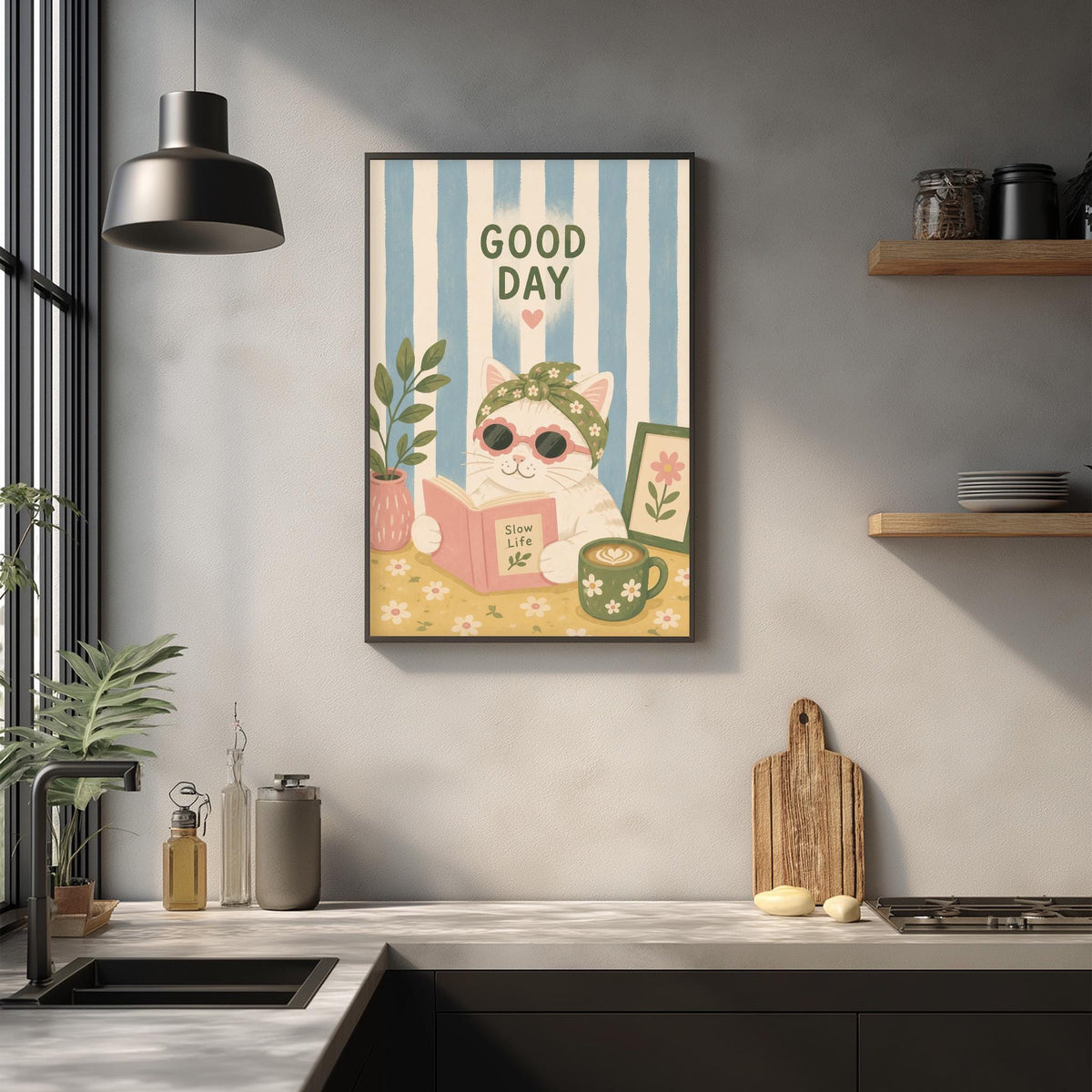 a kitchen counter with various items, including a framed poster of a cat reading a book, a wooden cutting board, and a potted plant.