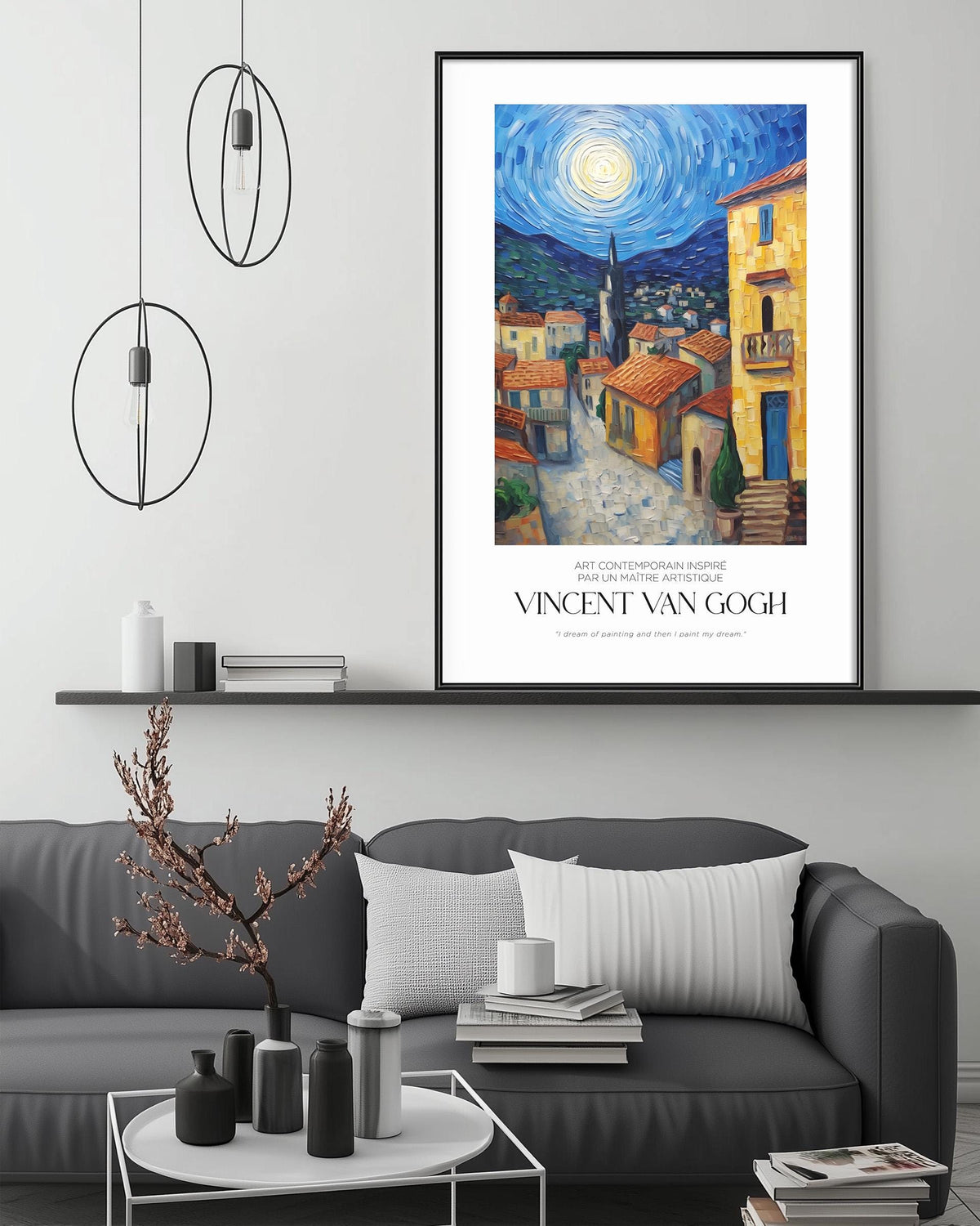 a large framed painting of a village scene with a bright blue sky and a yellow building, hanging on a wall above a gray couch with a coffee table in front of it.