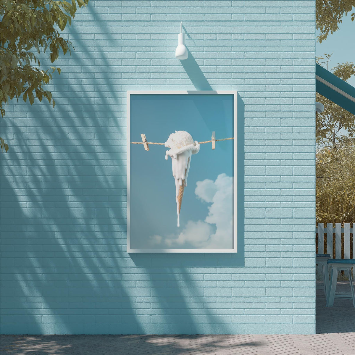 a large framed picture of an ice cream cone hanging from a clothesline against a blue brick wall.