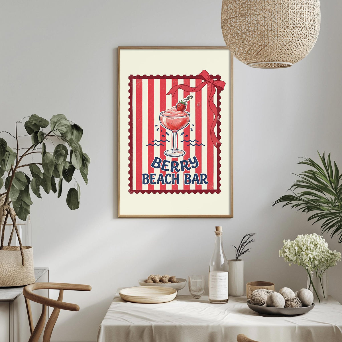 a framed poster of a red and white striped design with a glass of red wine and a strawberry on a beach bar sign, hanging on a wall above a dining table with various items on it.