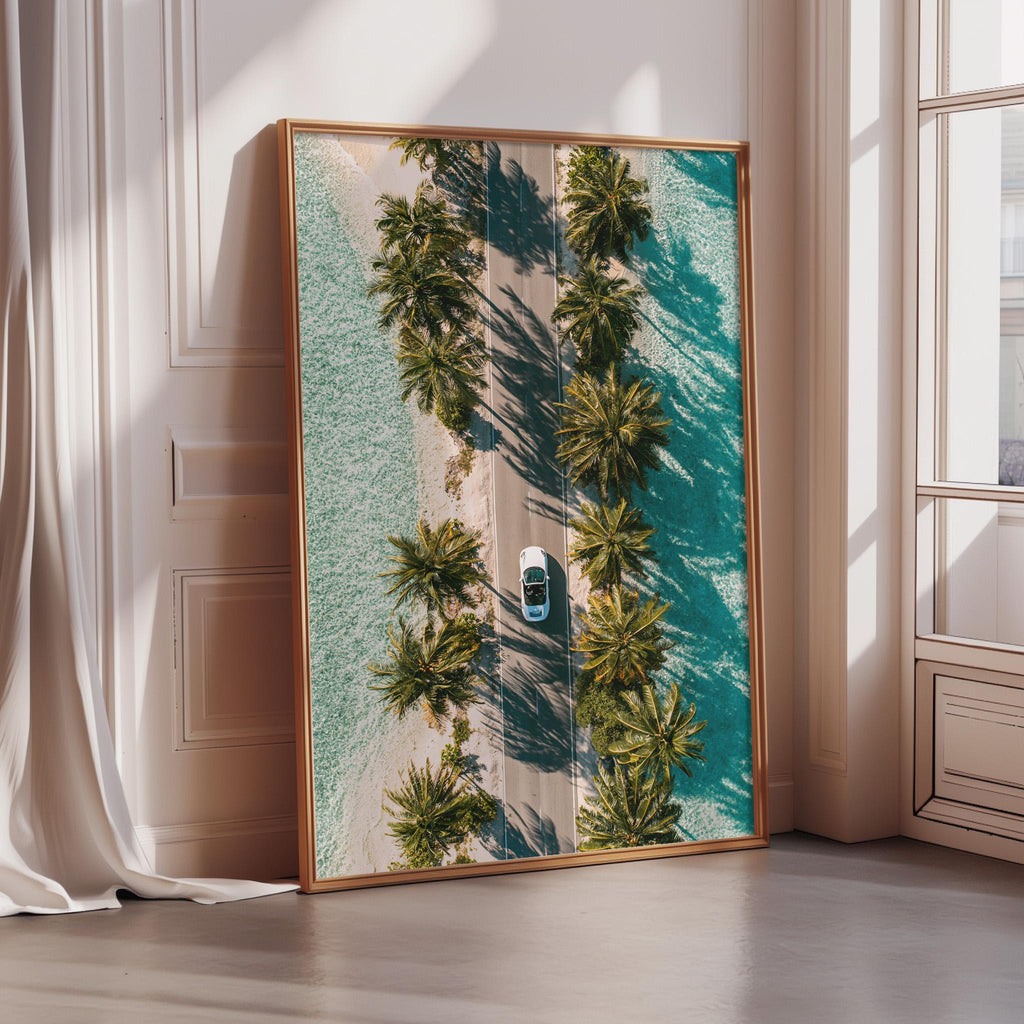 a large framed picture of a tropical beach scene with palm trees and a car driving down a road.