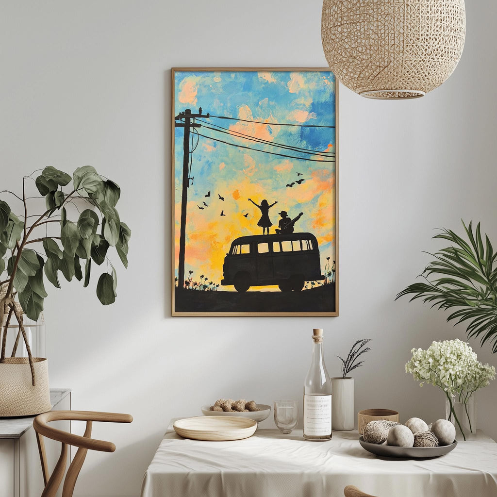 a framed painting of a van with silhouettes of people on top, set against a colorful sky with birds. The painting is hung on a wall above a dining table with various items on it, including a bottle, a bowl, and a vase.