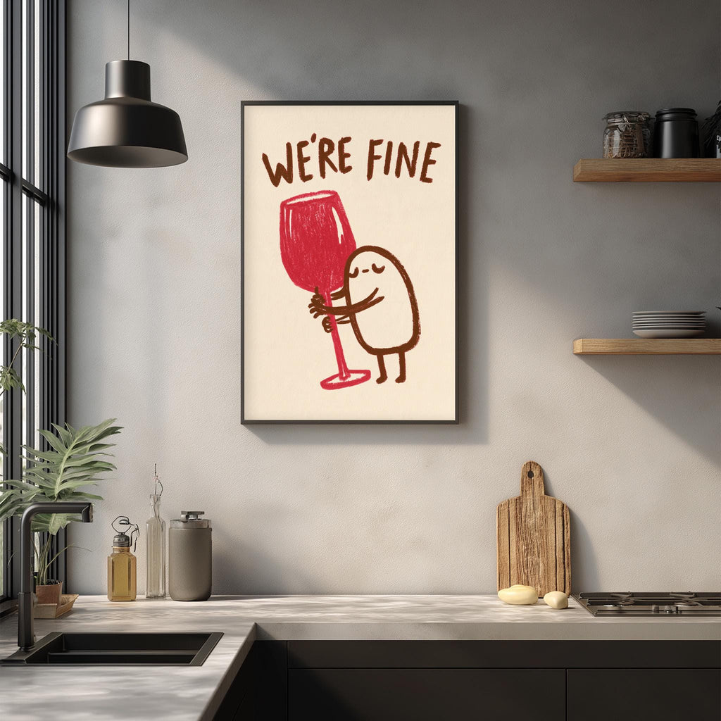 a kitchen counter with various kitchen items, including a wine glass, a cutting board, and a plant. Above the counter, there is a framed poster with a cartoon character holding a wine glass and the text "WE'RE FINE".