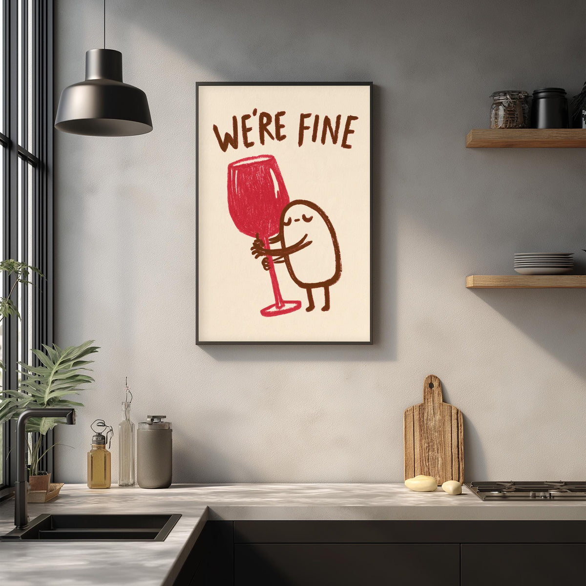 a kitchen counter with various kitchen items, including a wine glass, a cutting board, and a plant. Above the counter, there is a framed poster with a cartoon character holding a wine glass and the text "WE'RE FINE".