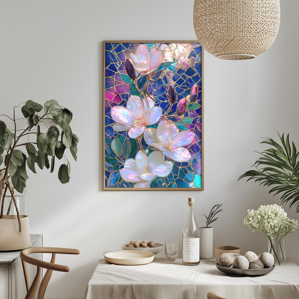 a dining table with a white tablecloth, a vase of white flowers, a bottle, and a bowl of fruit. Above the table, there is a framed painting of pink and purple flowers on a blue background.