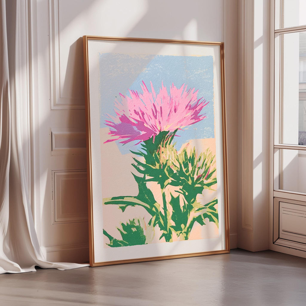 a large framed print of a vibrant pink flower with green leaves, displayed on a wall near a window.