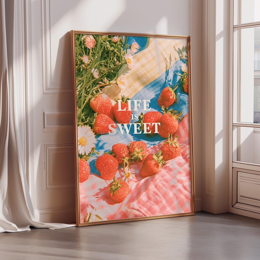a large framed poster with a vibrant display of strawberries and flowers, accompanied by the text "LIFE IS SWEET" in a playful and colorful style.