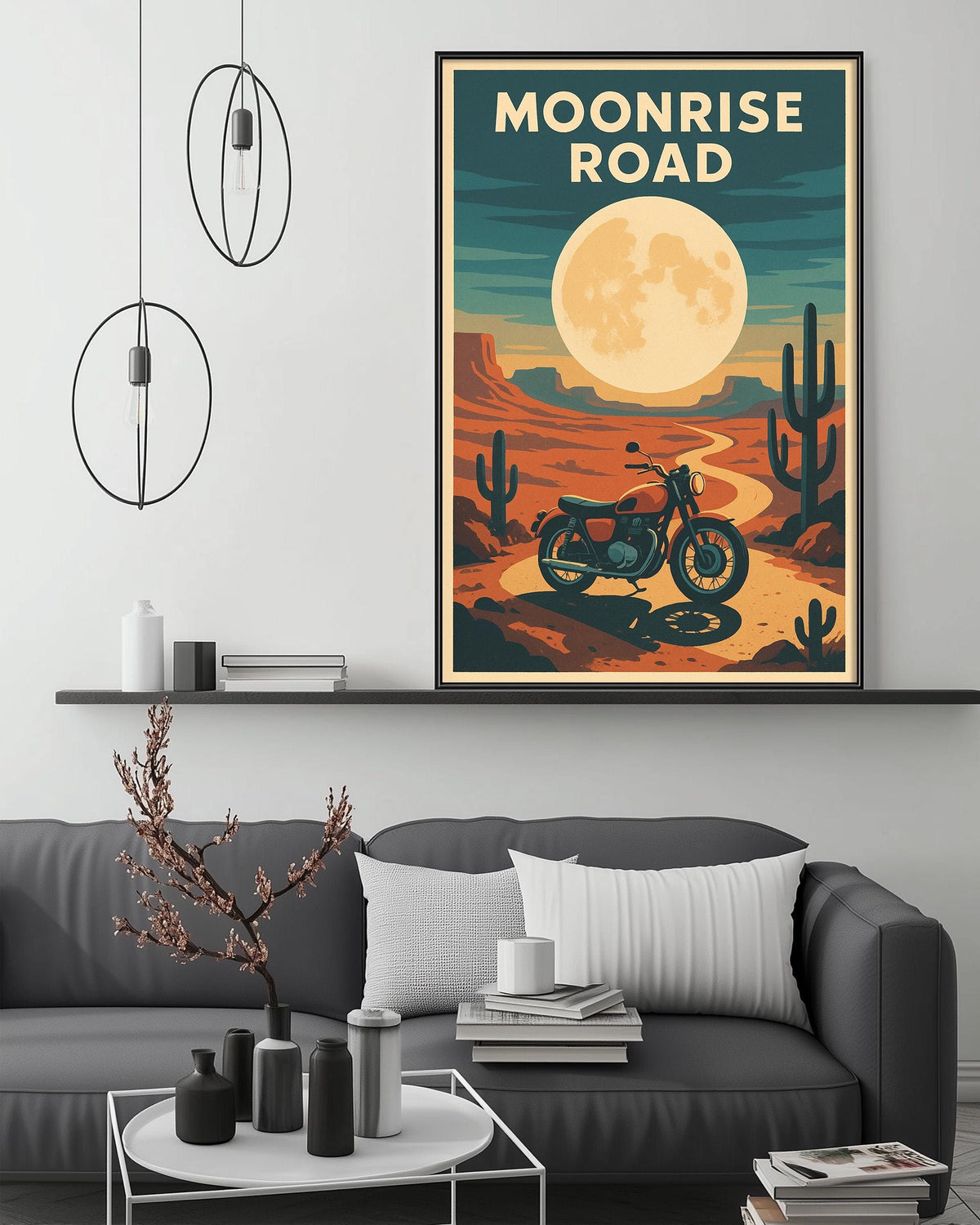 a poster of the "Moonrise Road" with a motorcycle, set against a desert landscape with a large moon. The poster is hanging on a wall above a gray couch, which has a coffee table in front of it. The room has a minimalist and modern design, with a few decorative items and a pendant light hanging from the ceiling.