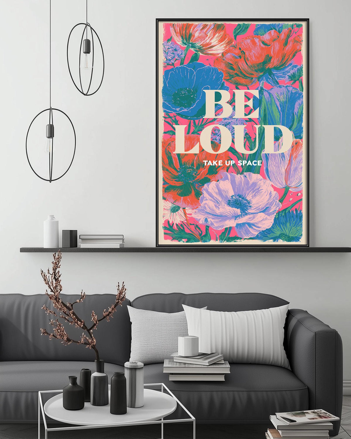 a living room with a gray couch, a coffee table, and a large framed poster with a floral design hanging on the wall above the couch.