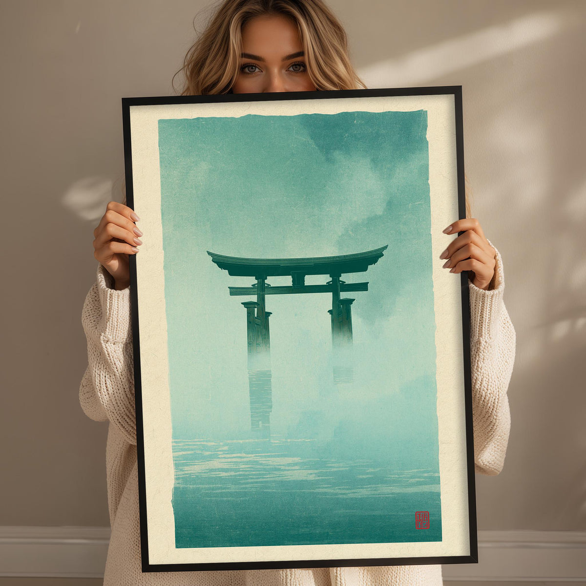 A woman holding a framed print of a Japanese torii gate in a misty landscape.