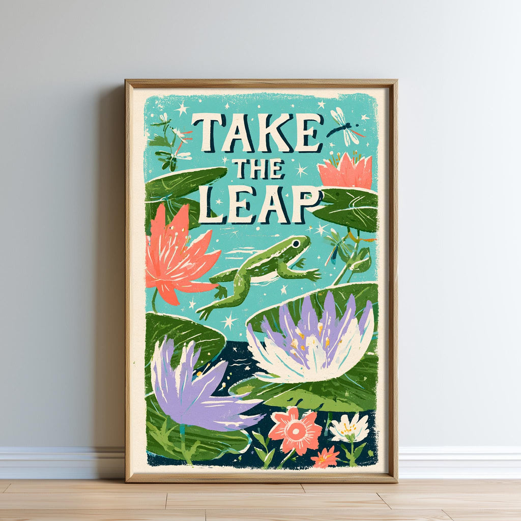 The image is a framed poster with a vibrant illustration of a frog leaping over a pond filled with colorful flowers and plants. The text "TAKE THE LEAP" is prominently displayed in the center of the poster.