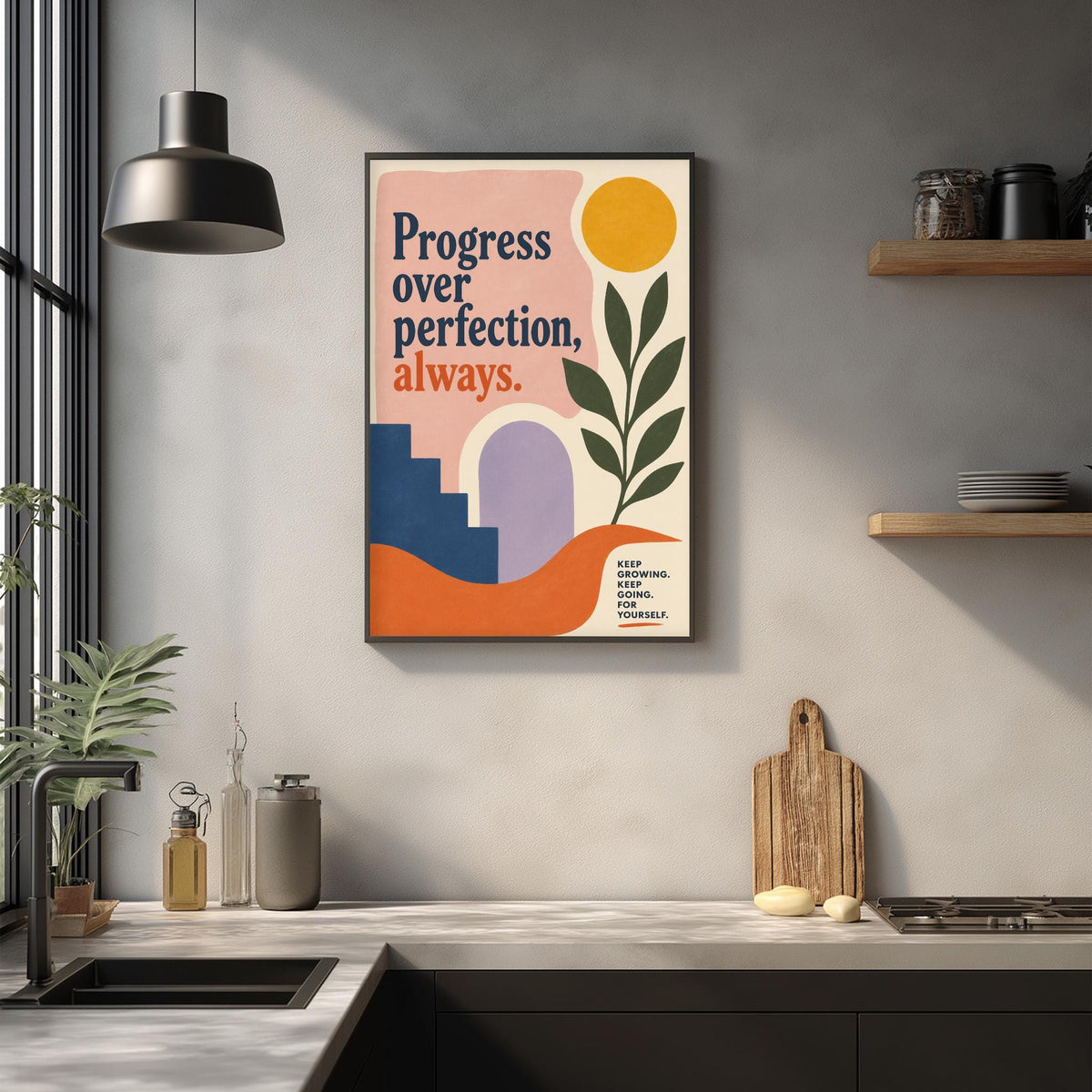 a kitchen counter with various kitchen items such as a cutting board, a soap dispenser, and a bottle. Above the counter, there is a framed poster with the text "Progress over perfection, always."