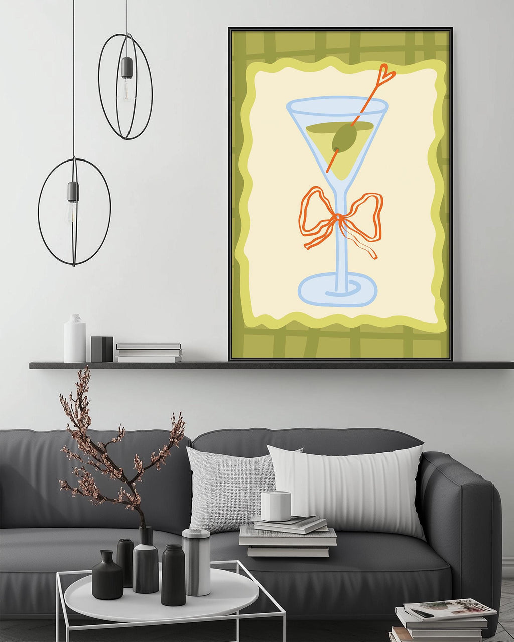 a living room with a gray couch, a coffee table, and a framed artwork of a martini glass with a heart-shaped object on it. The artwork is hanging on the wall above the couch.