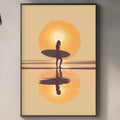 a framed artwork depicting a surfer standing on a beach at sunset, with the sun reflected in the water.