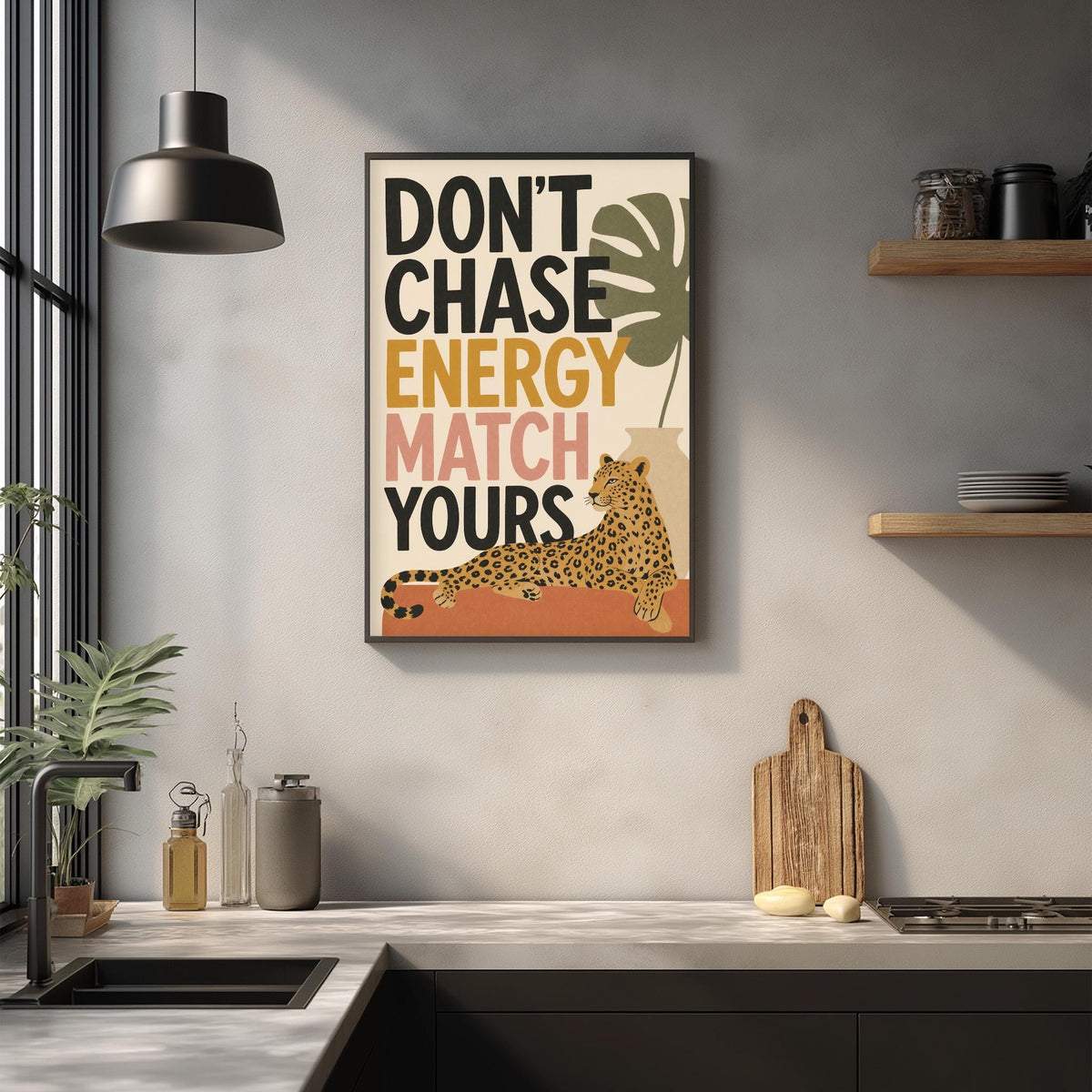 a kitchen counter with a framed poster hanging on the wall above it. The poster has a leopard graphic and the text "DON'T CHASE ENERGY MATCH YOURS" written on it.