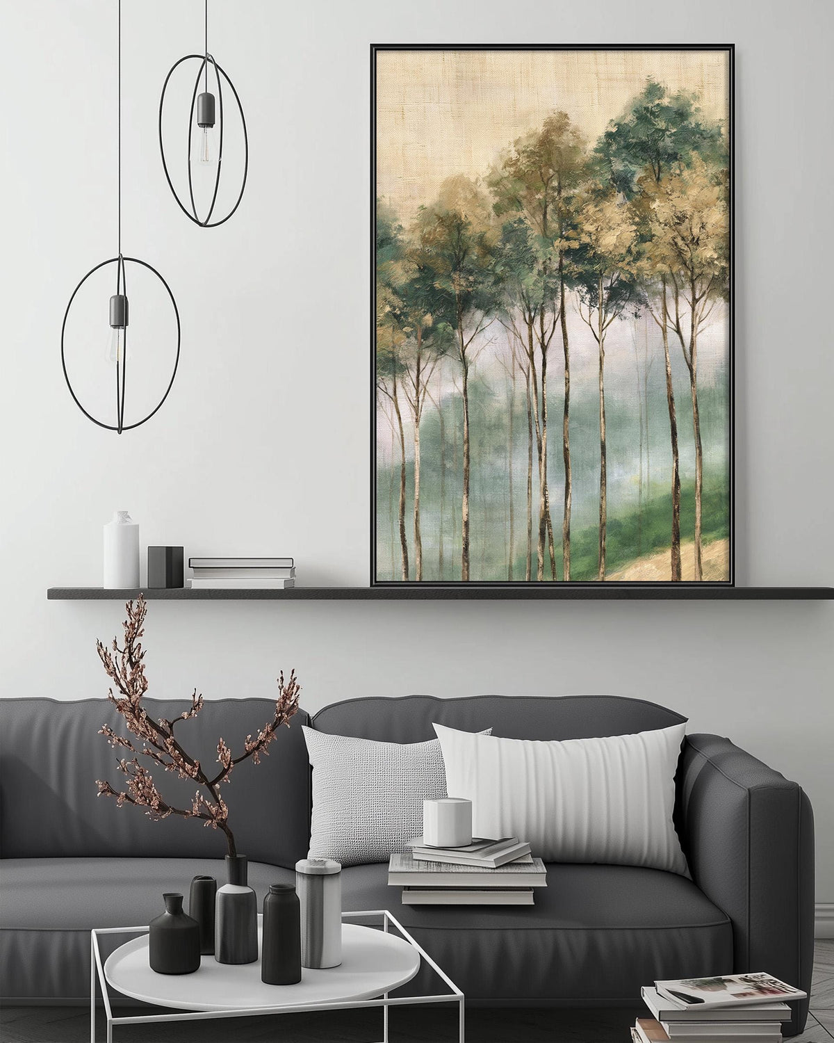a modern living room with a gray sofa, a coffee table, and a large painting of trees hanging above the sofa. The painting depicts a forest scene with tall trees and a misty atmosphere. The room has a minimalist and contemporary design, with a black pendant light hanging above the sofa and a shelf displaying decorative items.