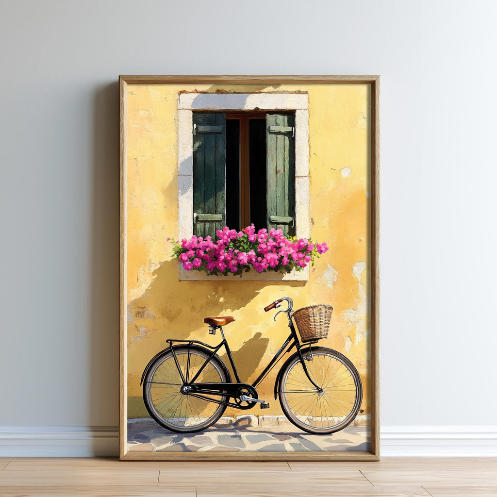 A framed painting depicting a bicycle parked in front of a yellow building with a window and flower box, set against a white wall.